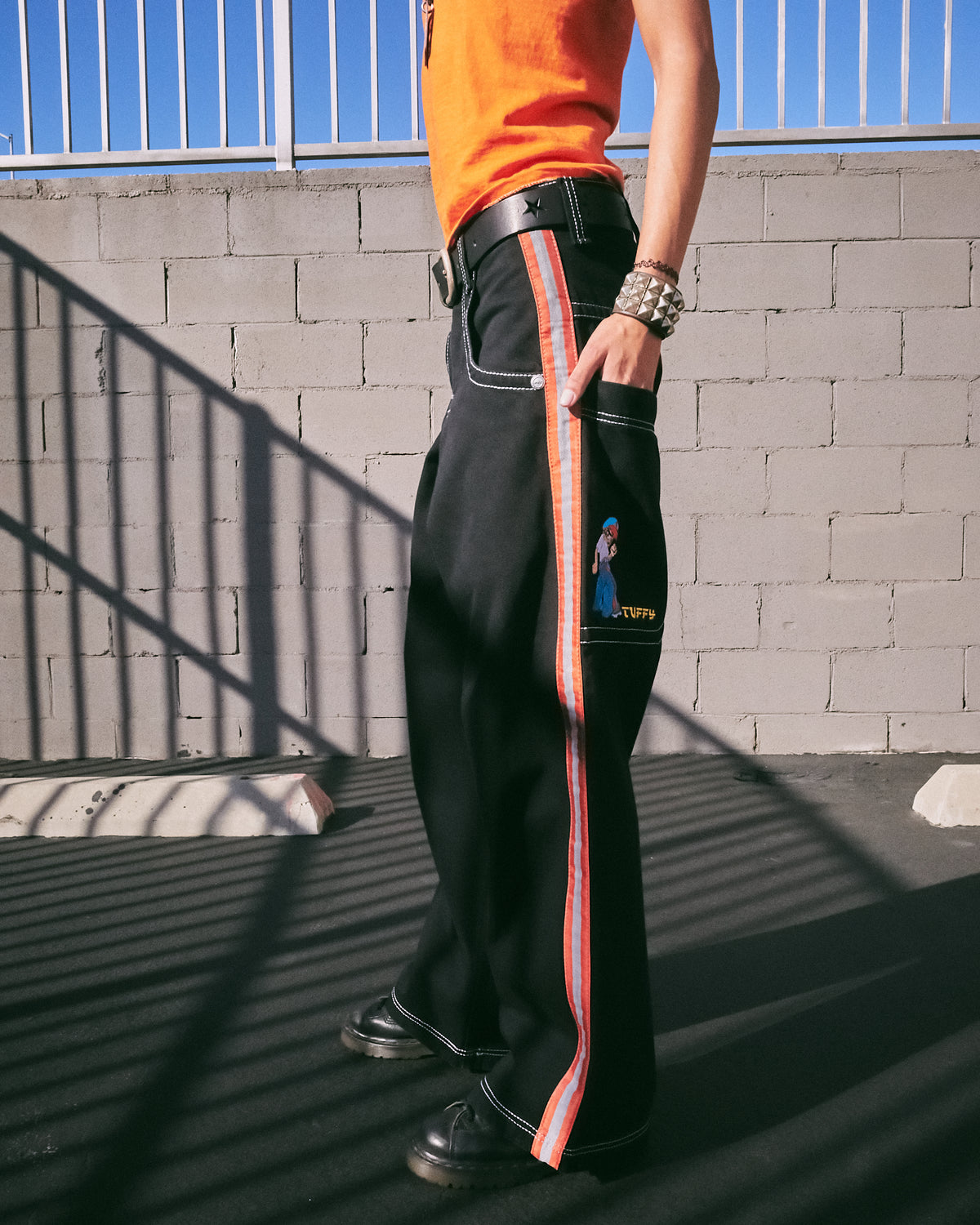 Model wearing the black wide-leg jeans, side view showing orange and reflective silver side stripe