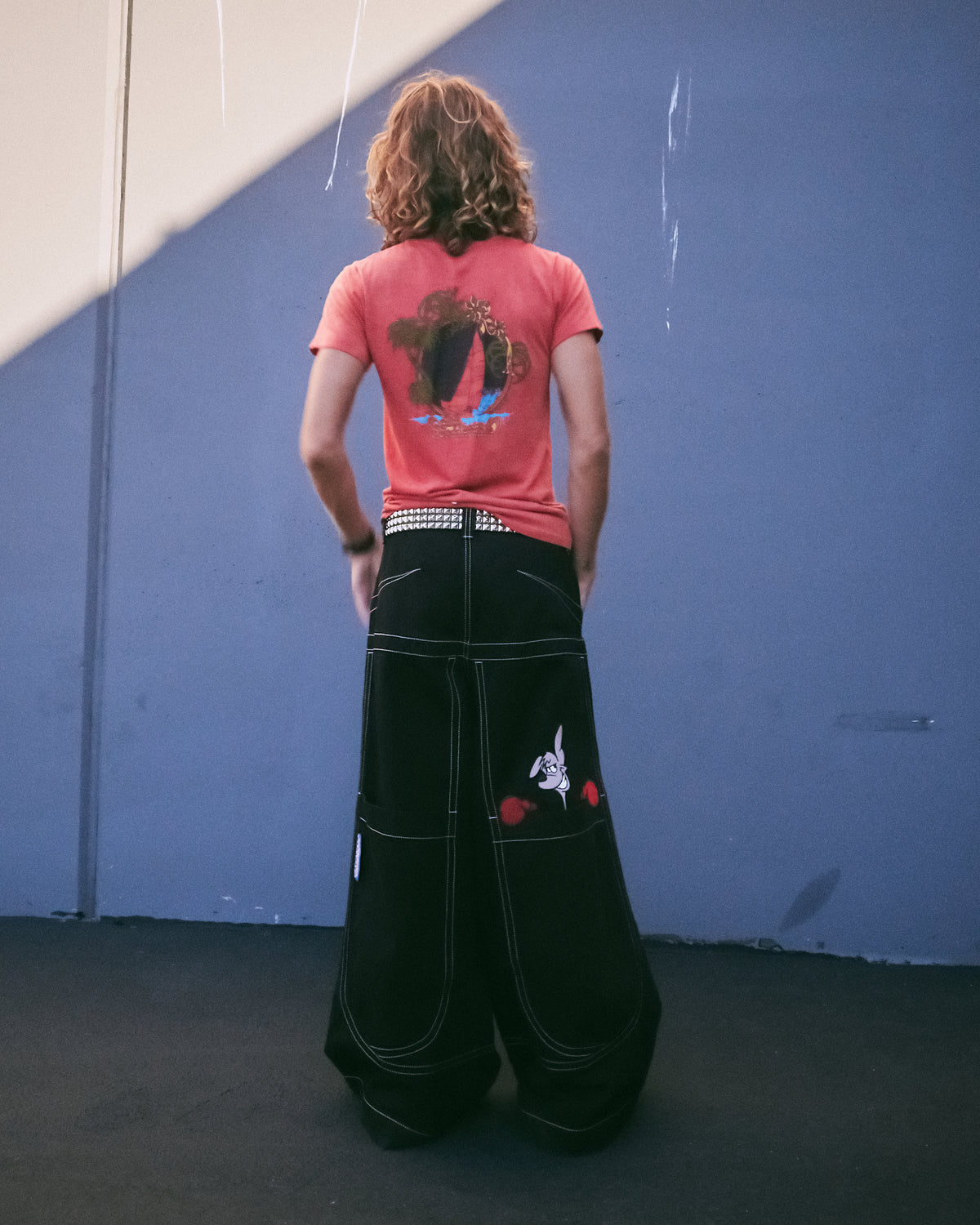 Model wearing very wide-leg black jeans, back view showing the kangaroo embroidery on the back pocket