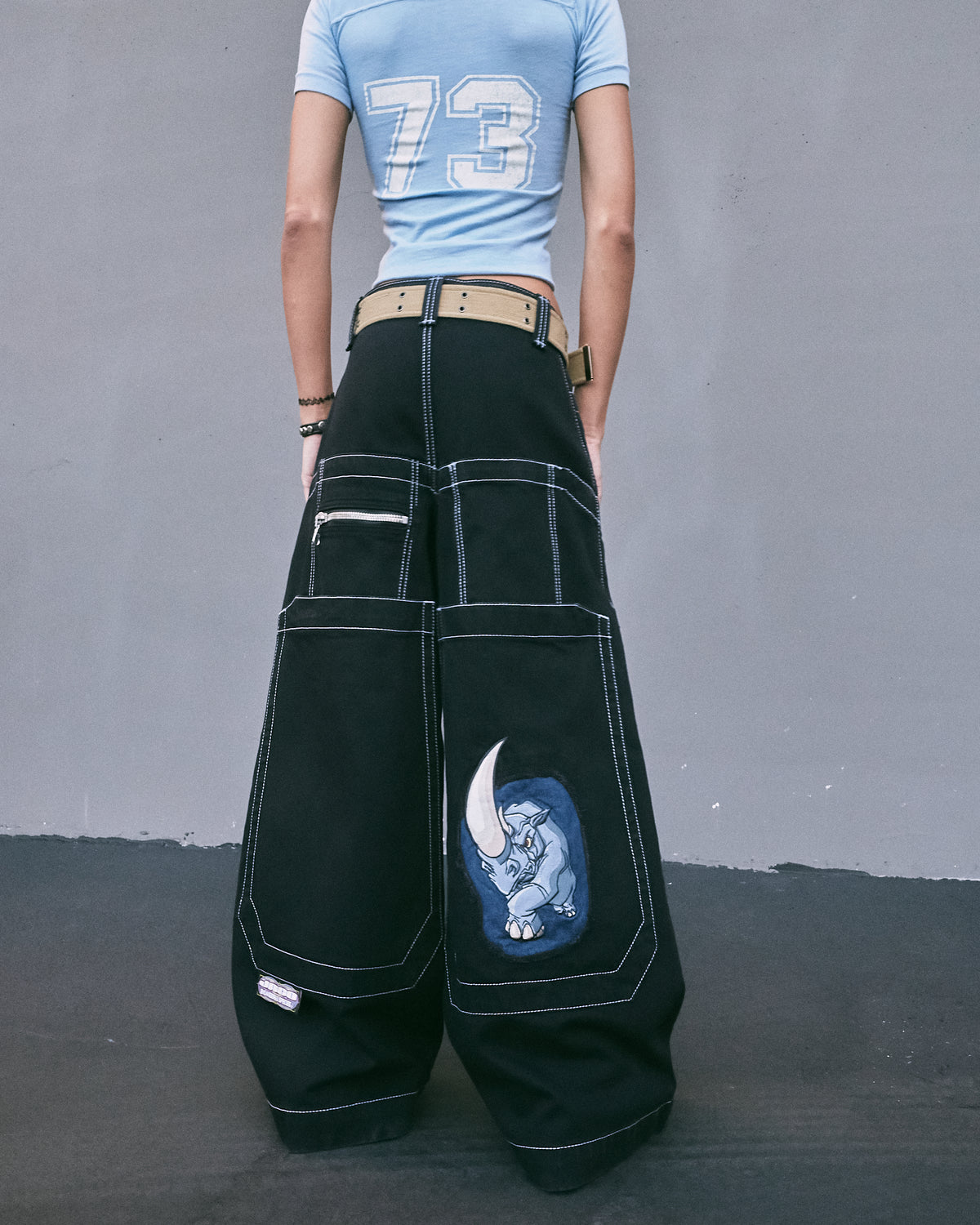 Back view of a model in the black wide-leg jeans showing the rhino embroidery, oversized back pockets and zip pocket