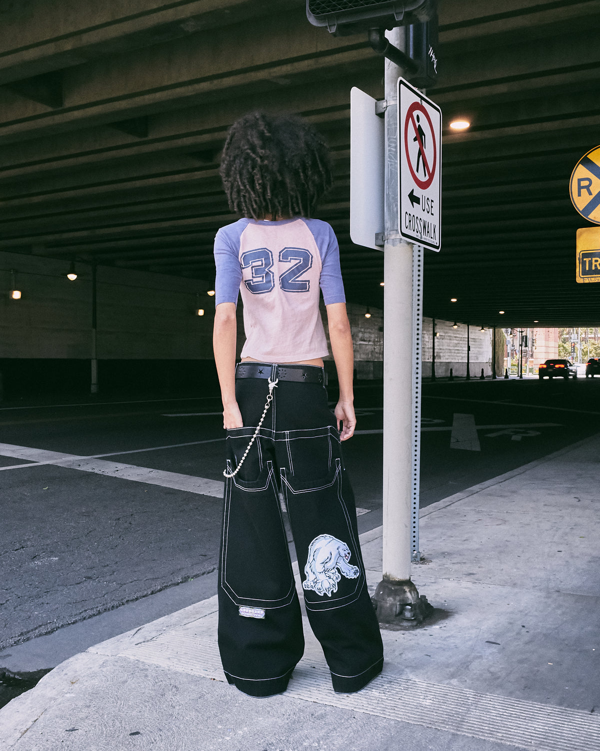Back view of a model in the wide-leg black jeans, showing the polar bear patch and oversized back pockets