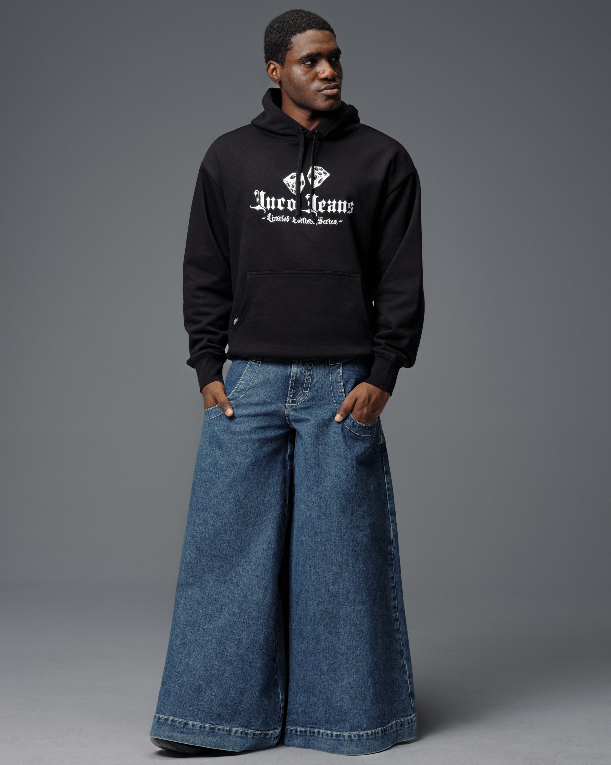 Model wearing enormous wide-leg JNCO jeans with a black hoodie in a modern Y2K streetwear image