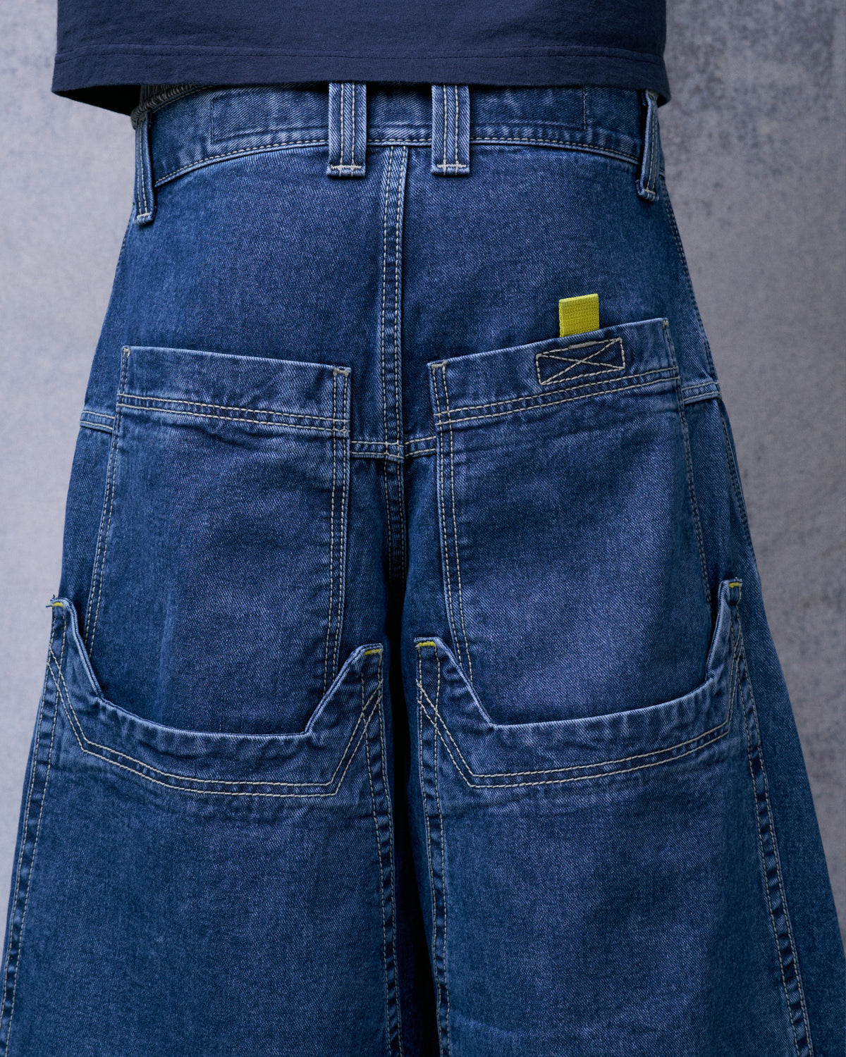 Close-up of the jeans worn from behind, showing double-layered back pockets and a yellow pull tab