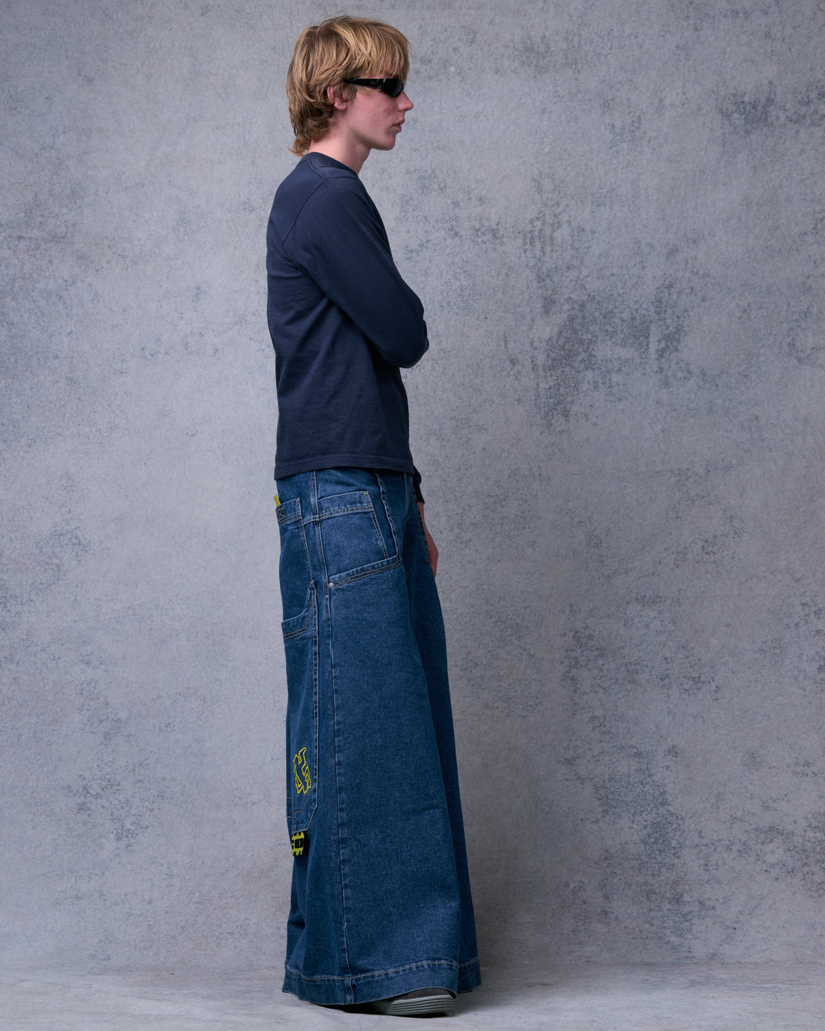 Model wearing the wide-leg dark stone jeans in full side profile, showing the leg width down to the floor