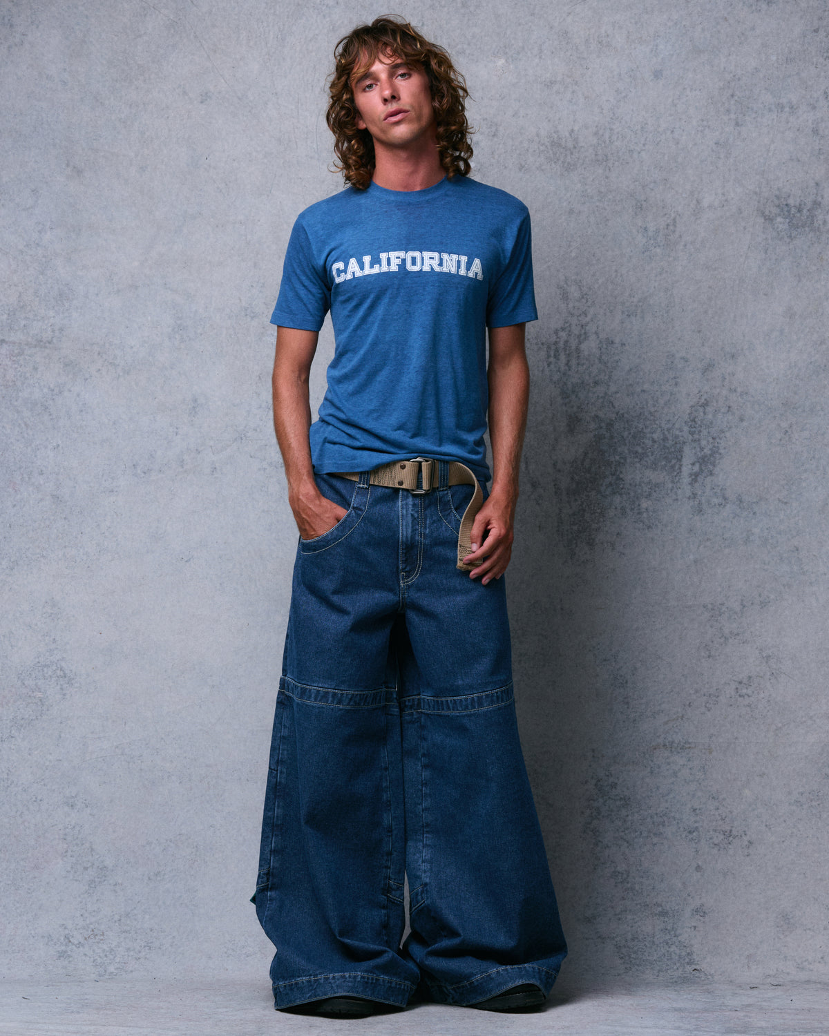 Model wearing dark stone wash extra-wide-leg jeans with a knee seam and khaki web belt, full-length front view