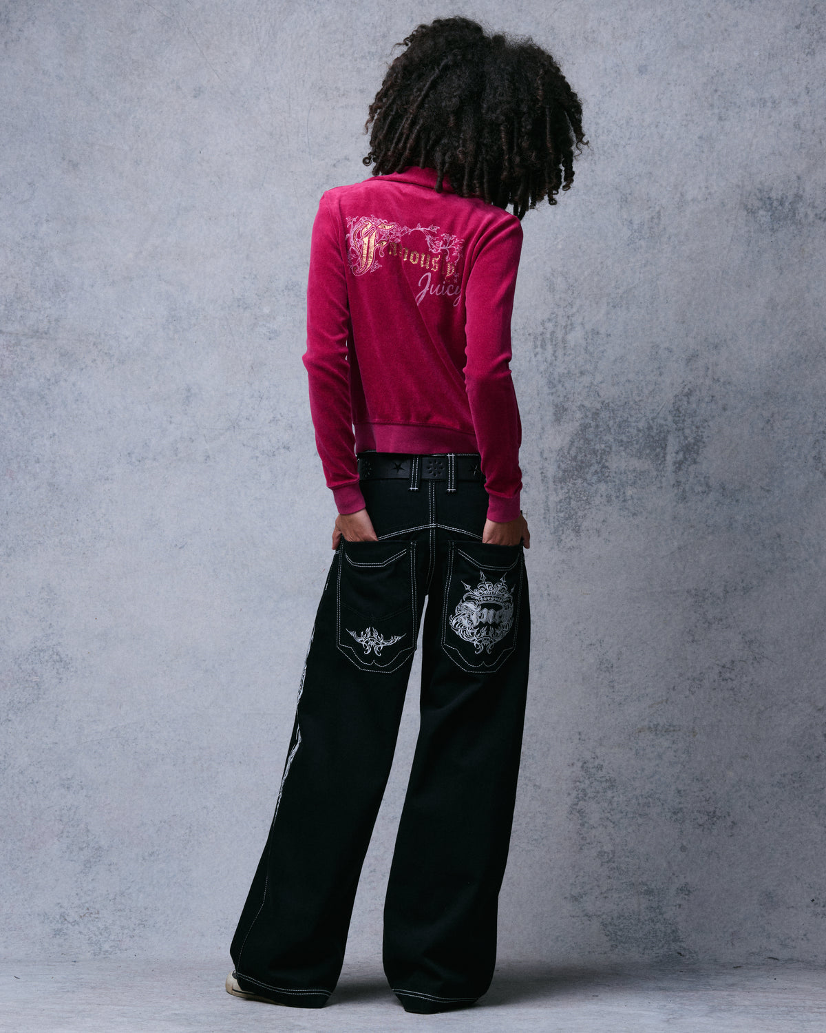 Back view of the black wide-leg jeans with the model's hands in the embroidered back pockets