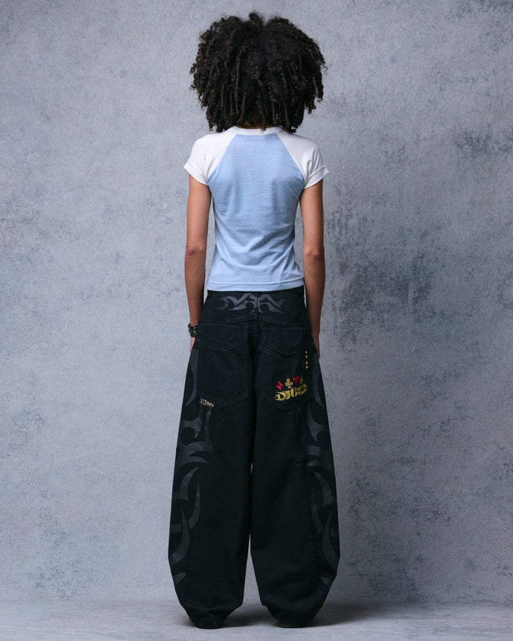 Model wearing the black wide-leg jeans, straight back view showing the full balloon leg width and tribal print