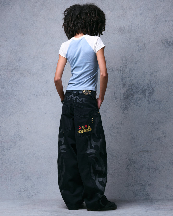 Model wearing the black wide-leg jeans, three-quarter back view with gold and red card-suit pocket embroidery