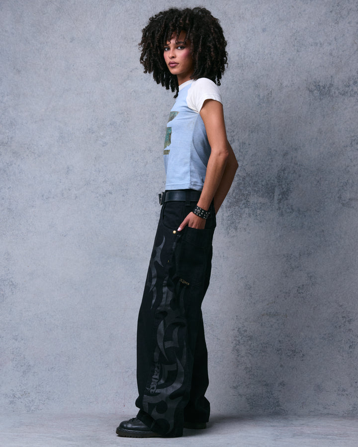 Model wearing the black wide-leg jeans, side view showing tribal print down the leg and a gold side pocket tag