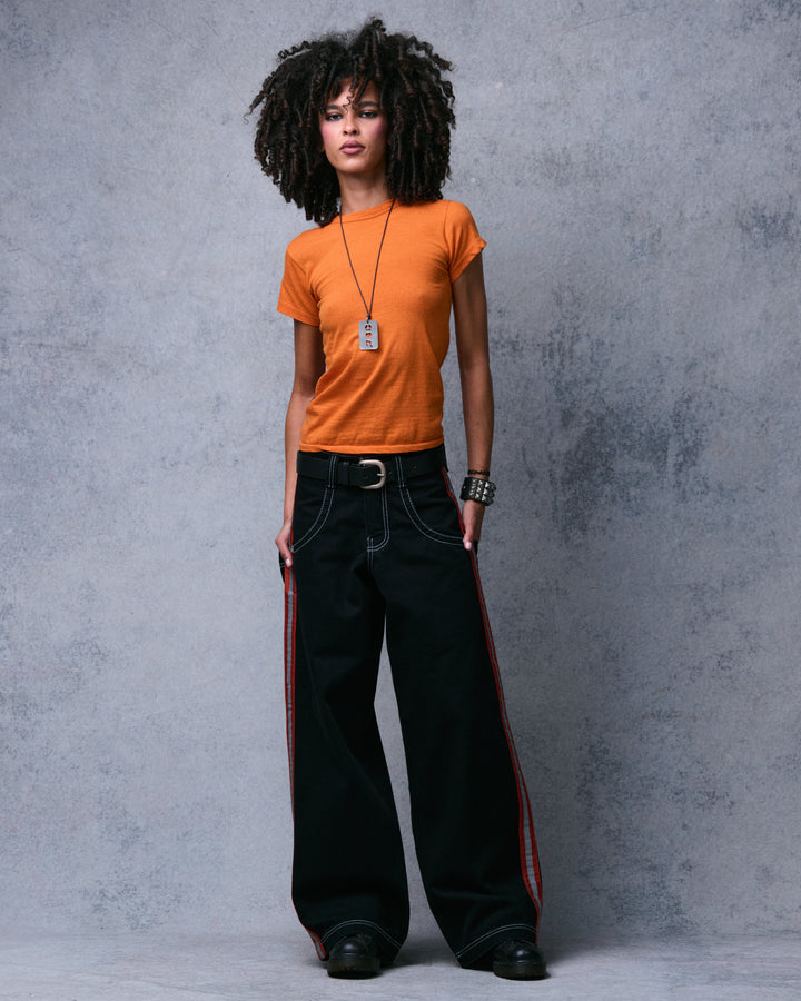 Model standing in the black wide-leg jeans, front view showing stripes down both outer legs