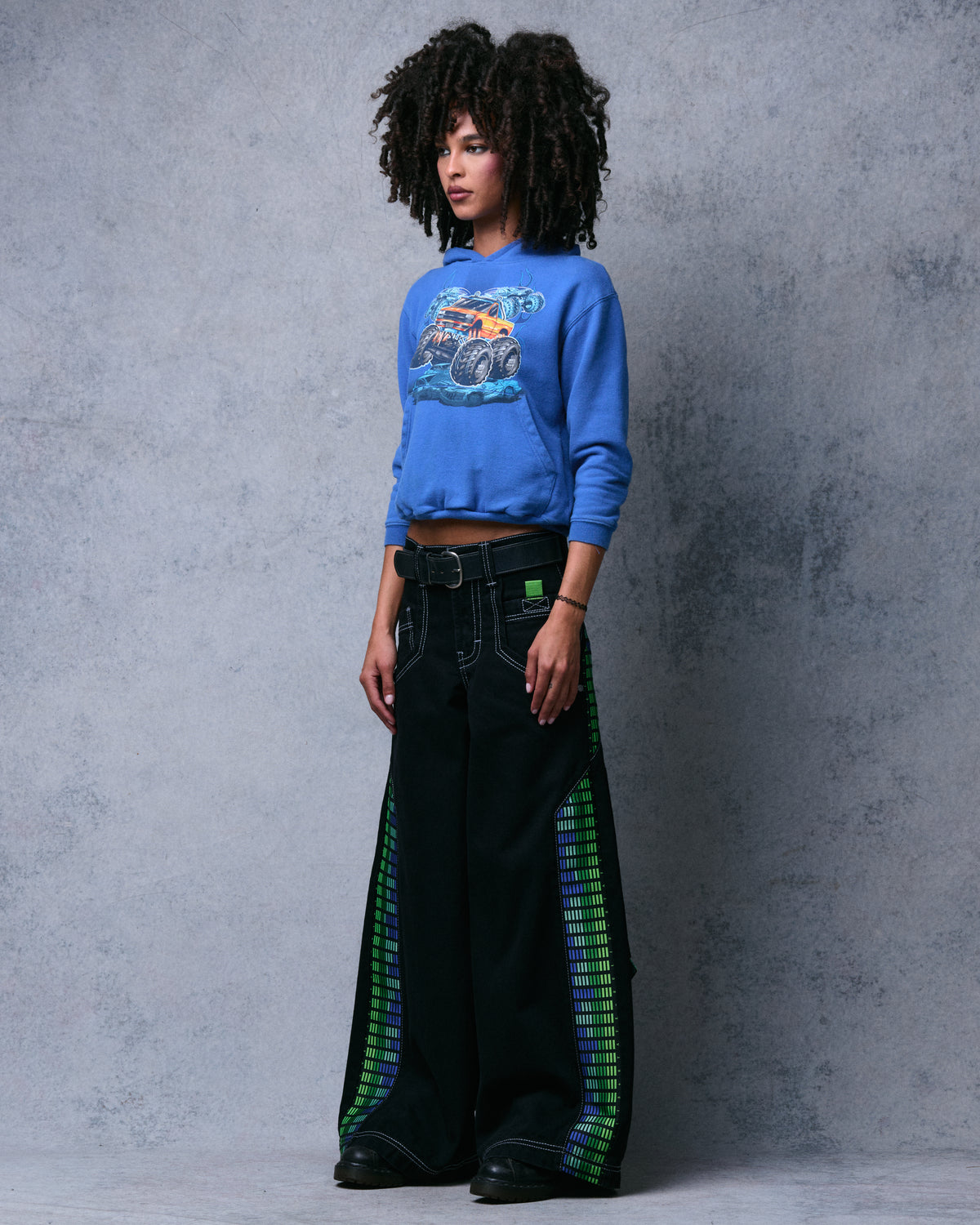 Model wearing the black wide-leg jeans with equalizer-bar side panels, three-quarter side view