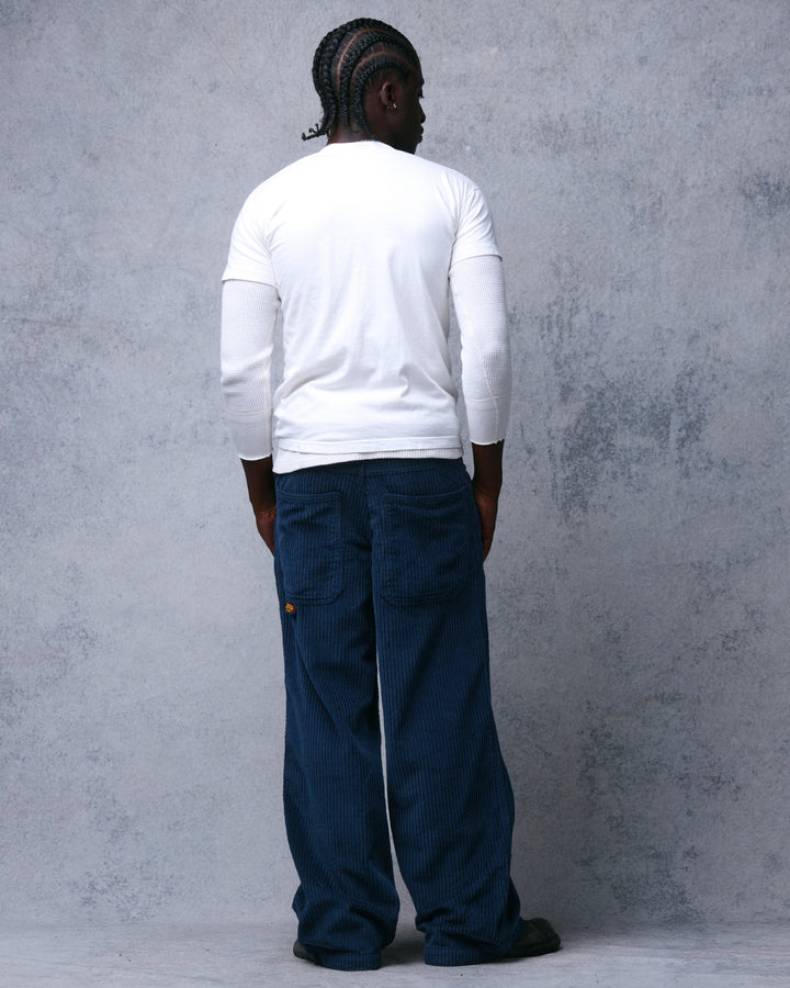 Model wearing navy wide-leg corduroy pants, full-length back view showing both back pockets