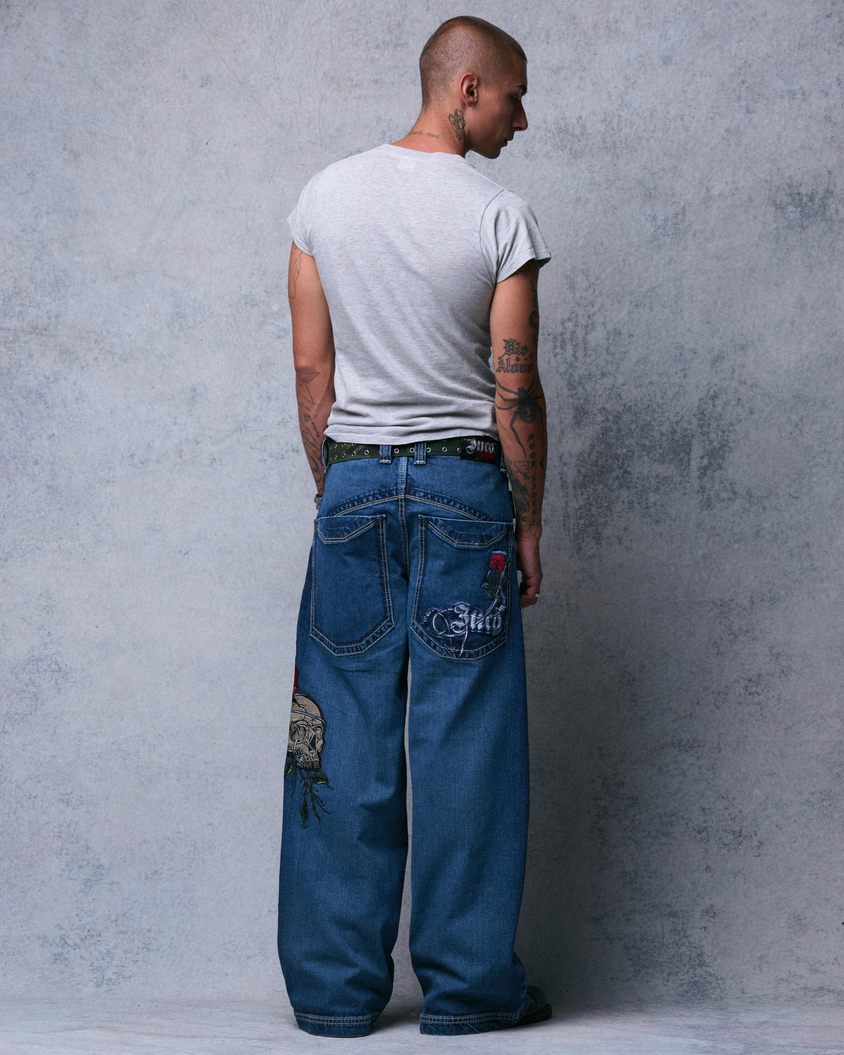 Rear view of a model in the wide-leg jeans looking over a shoulder, with the rose and Jnco back pocket embroidery visible