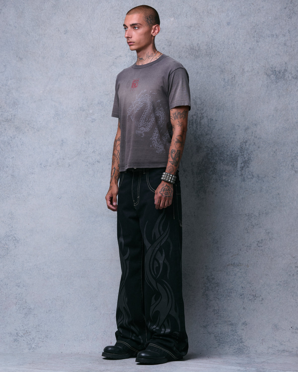 Model wearing black wide-leg jeans with tonal flame print, three-quarter front view from the left, full length
