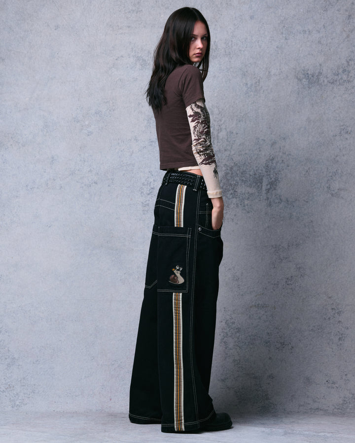 Model wearing the black wide-leg jeans, rear three-quarter view with snail embroidery and striped tape