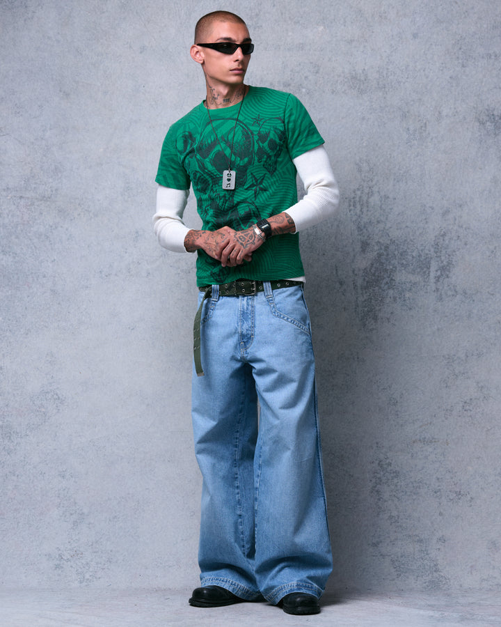Model wearing light-wash wide-leg jeans with a studded belt and green graphic tee, full-length front view