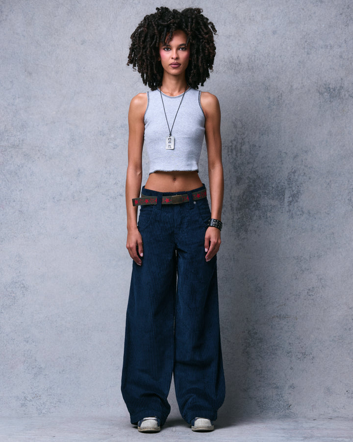 Model wearing navy wide-leg corduroy pants with a star belt and grey crop top, full front view