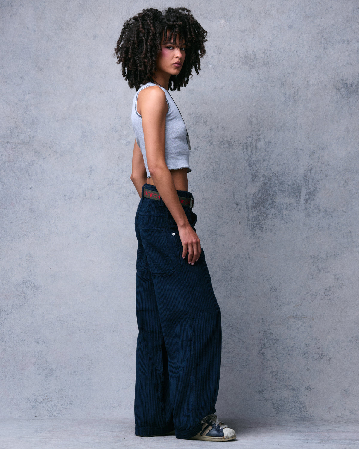 Model wearing navy wide-leg wide-wale corduroy pants, rear three-quarter view looking over shoulder