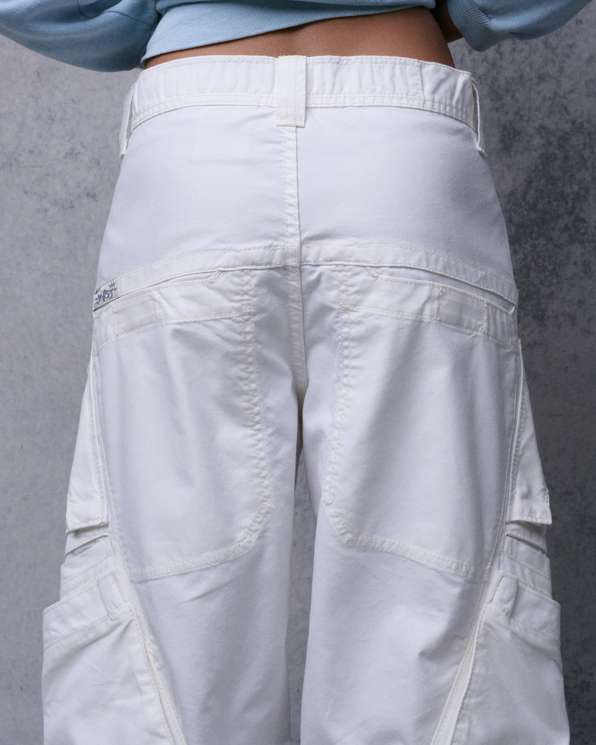Back view of off-white cargo pants on a model, showing waistband, back welt pockets, curved seams and side cargo pockets