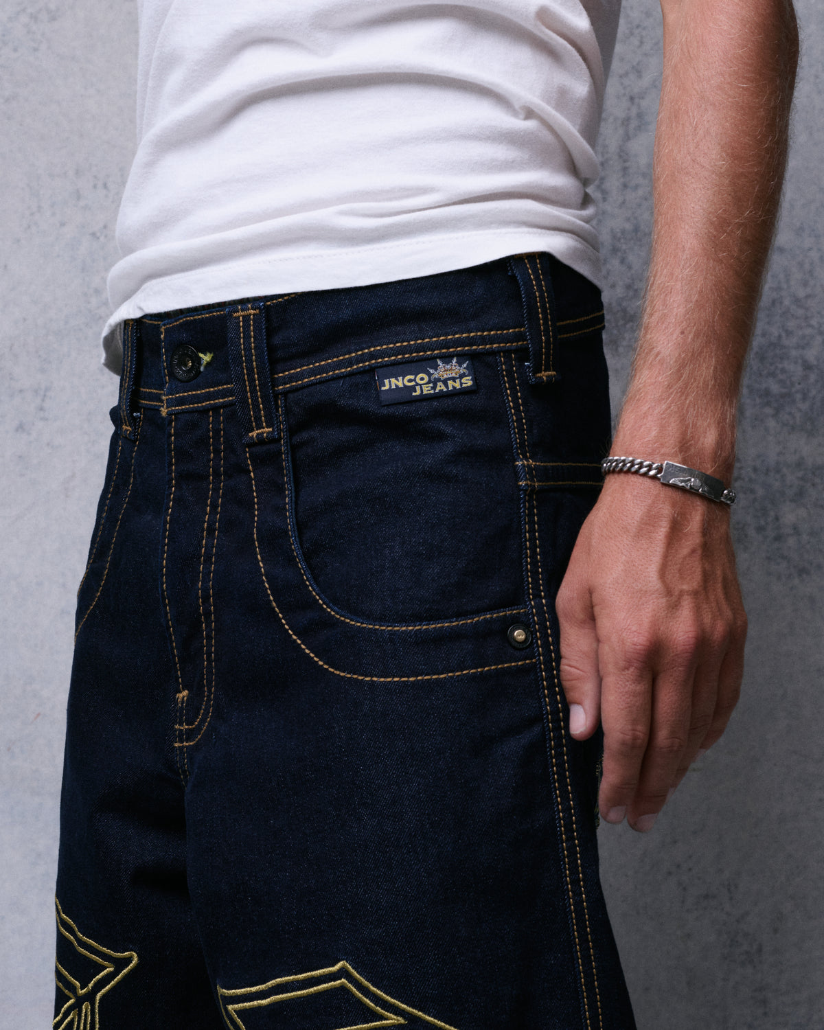 Close-up of the front pocket and waistband with gold contrast stitching and a small JNCO Jeans label