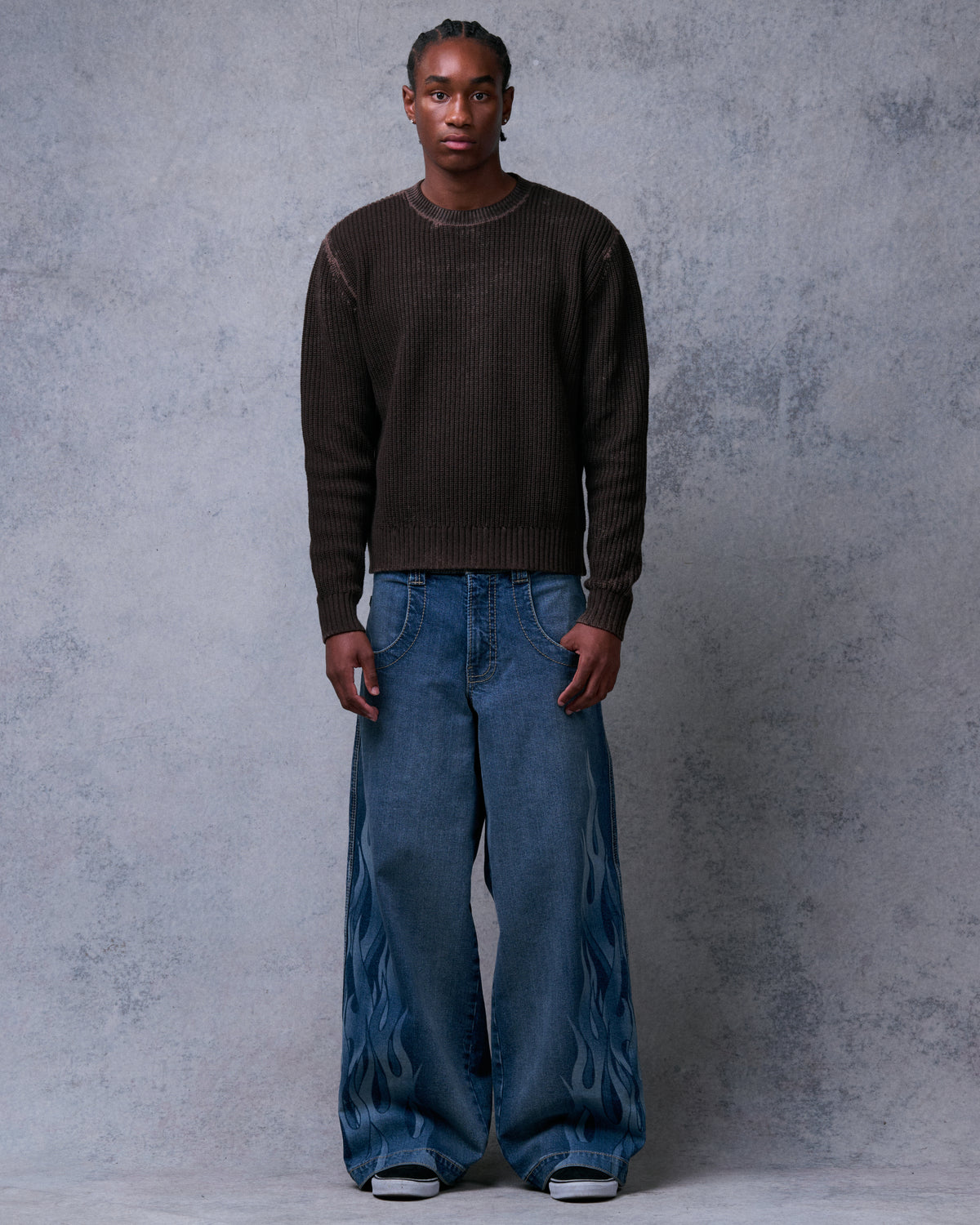 Model wearing wide-leg blue jeans with tonal flame print on the outer legs, front view, full length