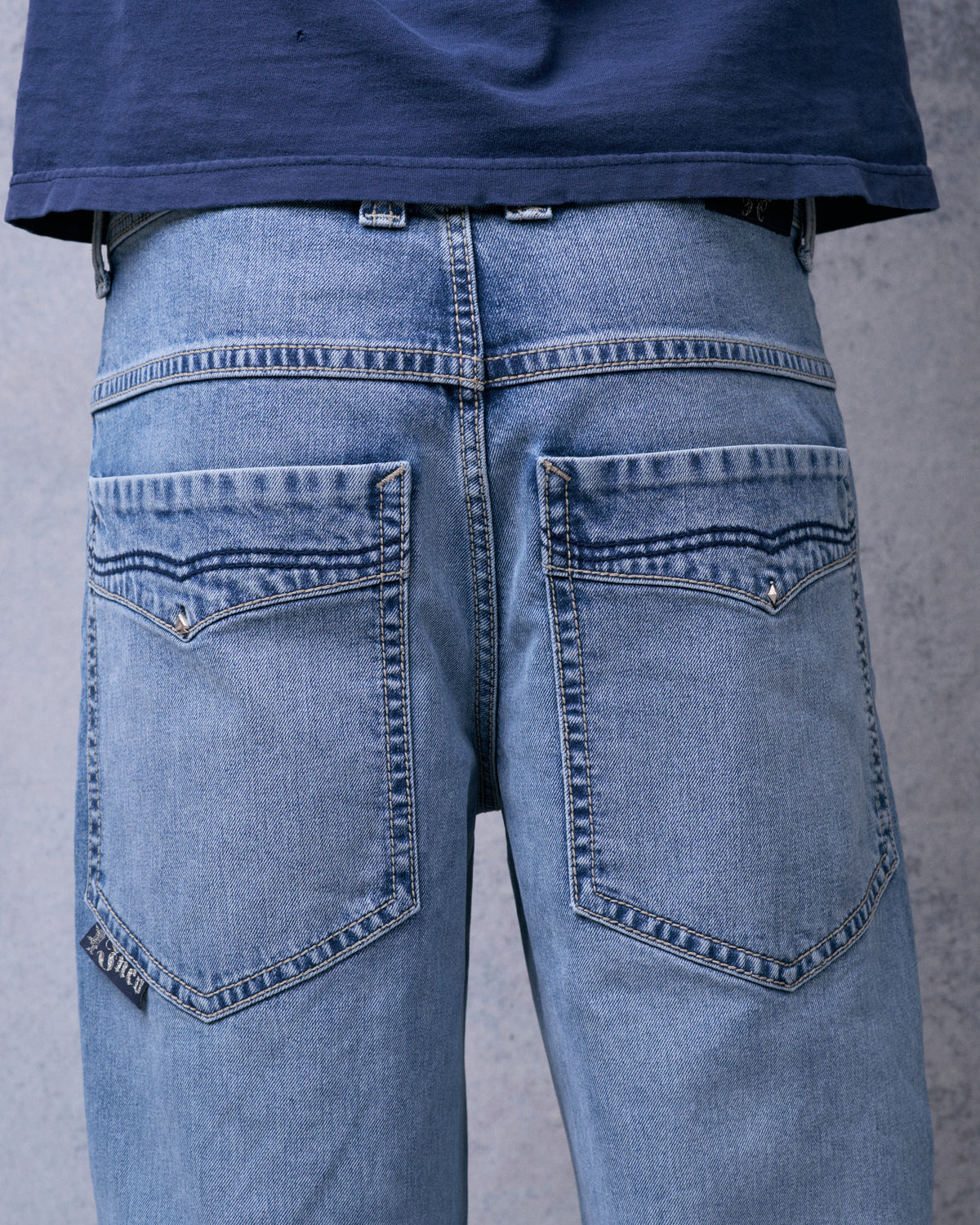 Back of light blue wide-leg jeans showing both rear pockets with diamond studs and contrast stitching