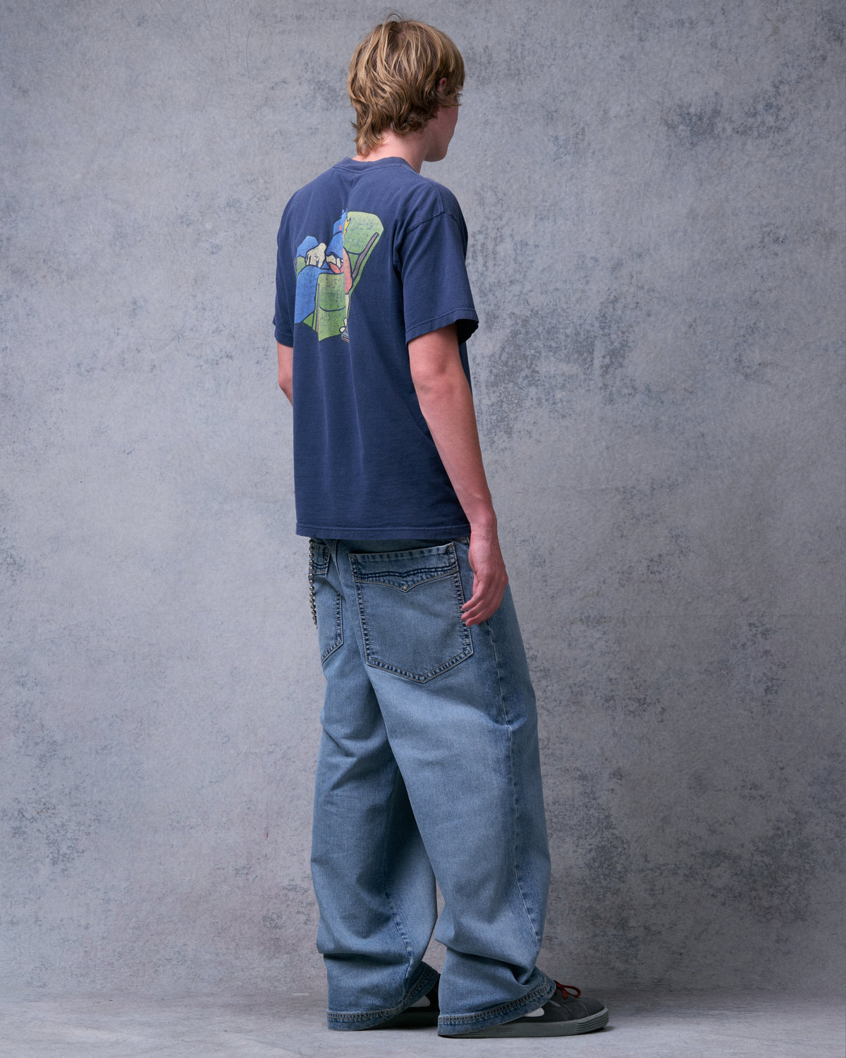 Model wearing light blue wide-leg jeans, three-quarter back view showing a back pocket and stacked hem
