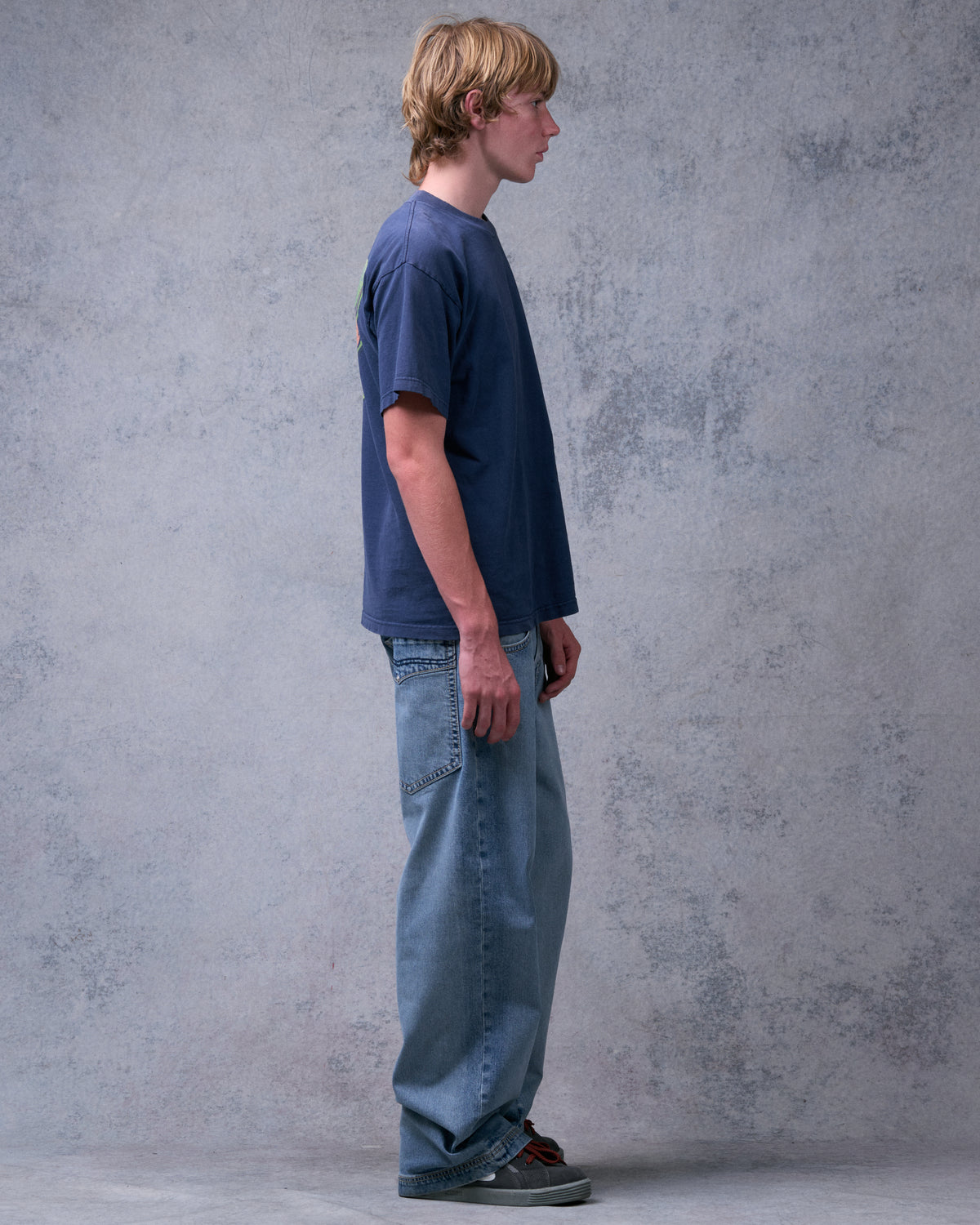 Model wearing light blue wide-leg jeans, right side profile showing the full-length loose leg
