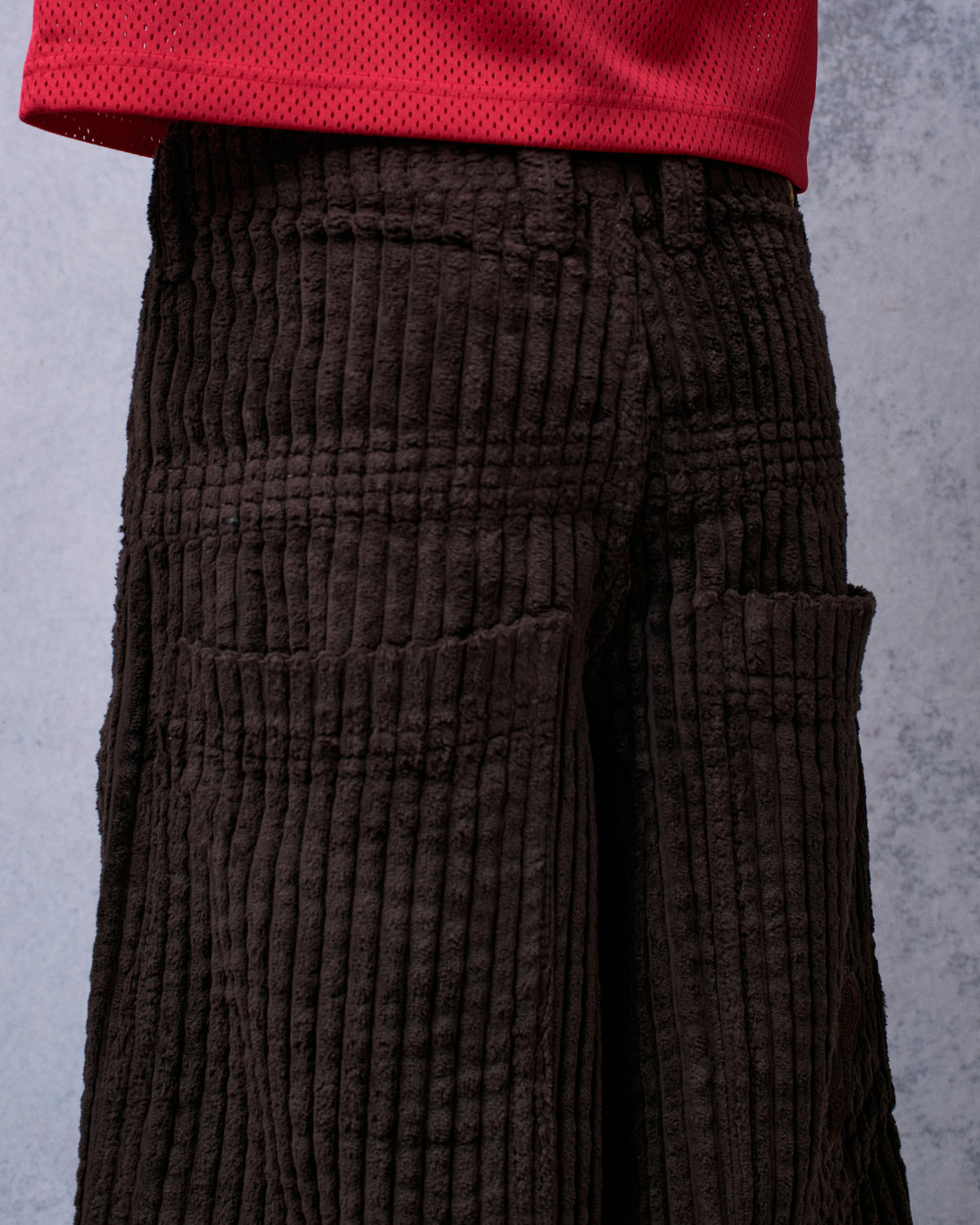 Close-up of the back of brown wide-leg corduroy pants on a model, showing back pockets and thick cord texture