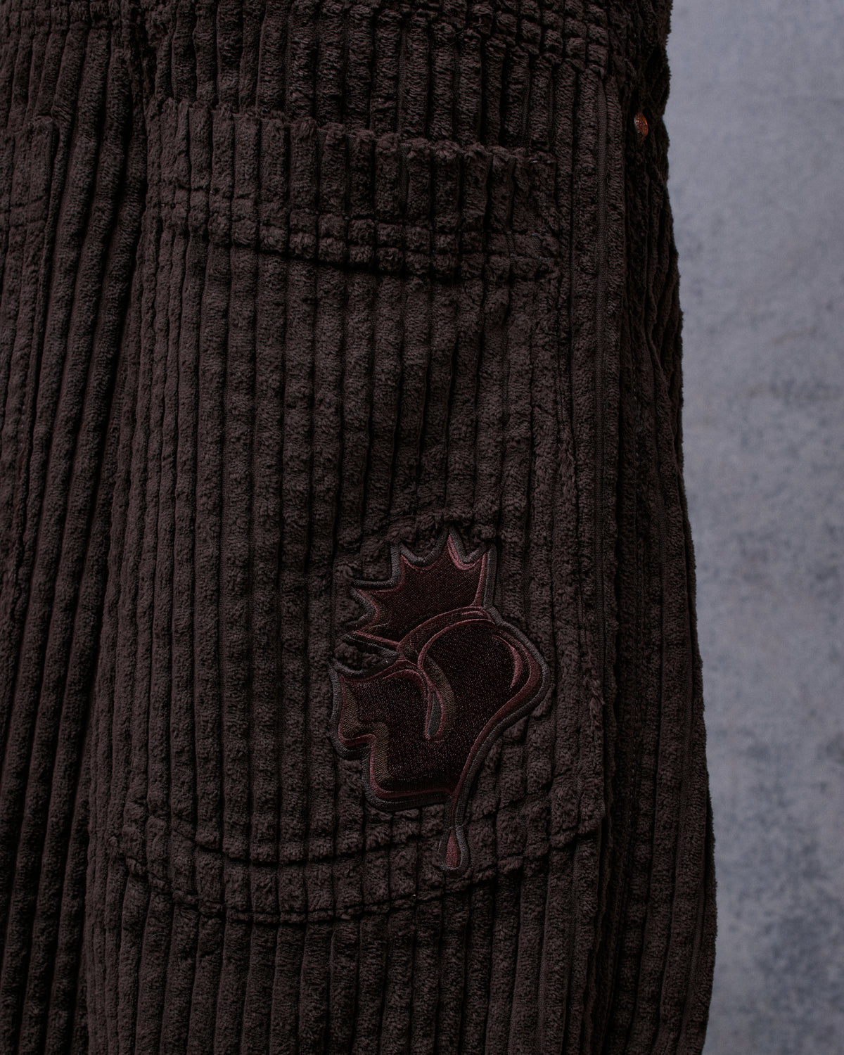 Close-up of the tonal embroidered crowned J patch below a back pocket on brown corduroy
