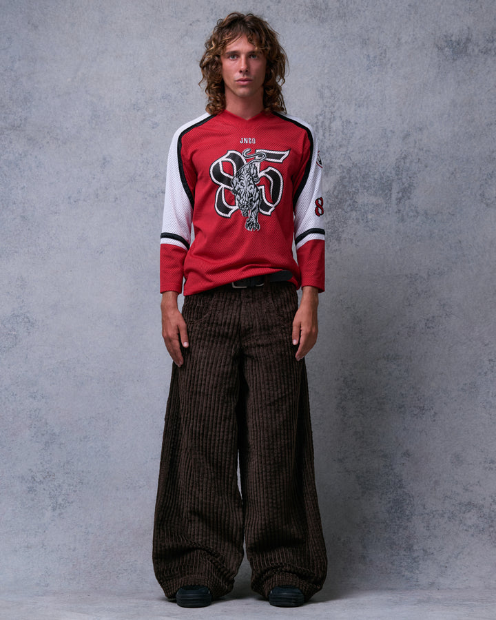 Model wearing brown wide-leg corduroy pants with a red jersey tucked behind a belt, full-length front view