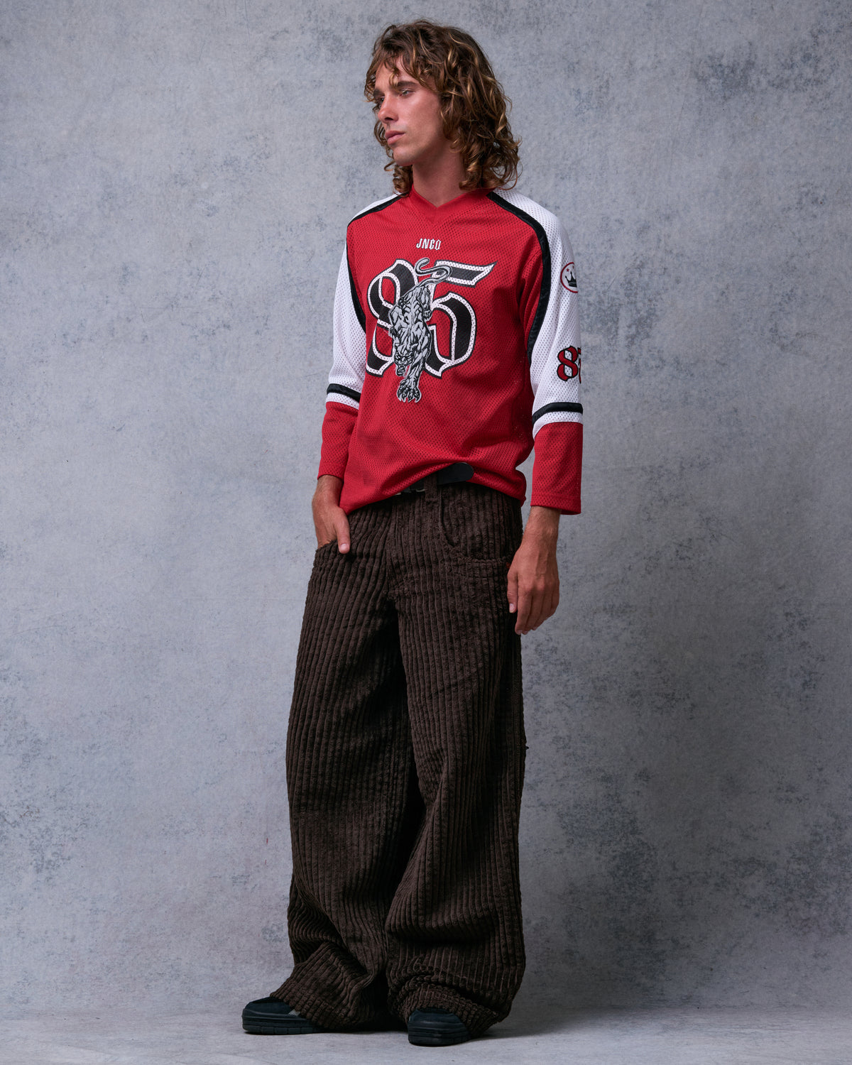 Model wearing brown wide-leg corduroy pants with one hand in the front pocket, angled front view