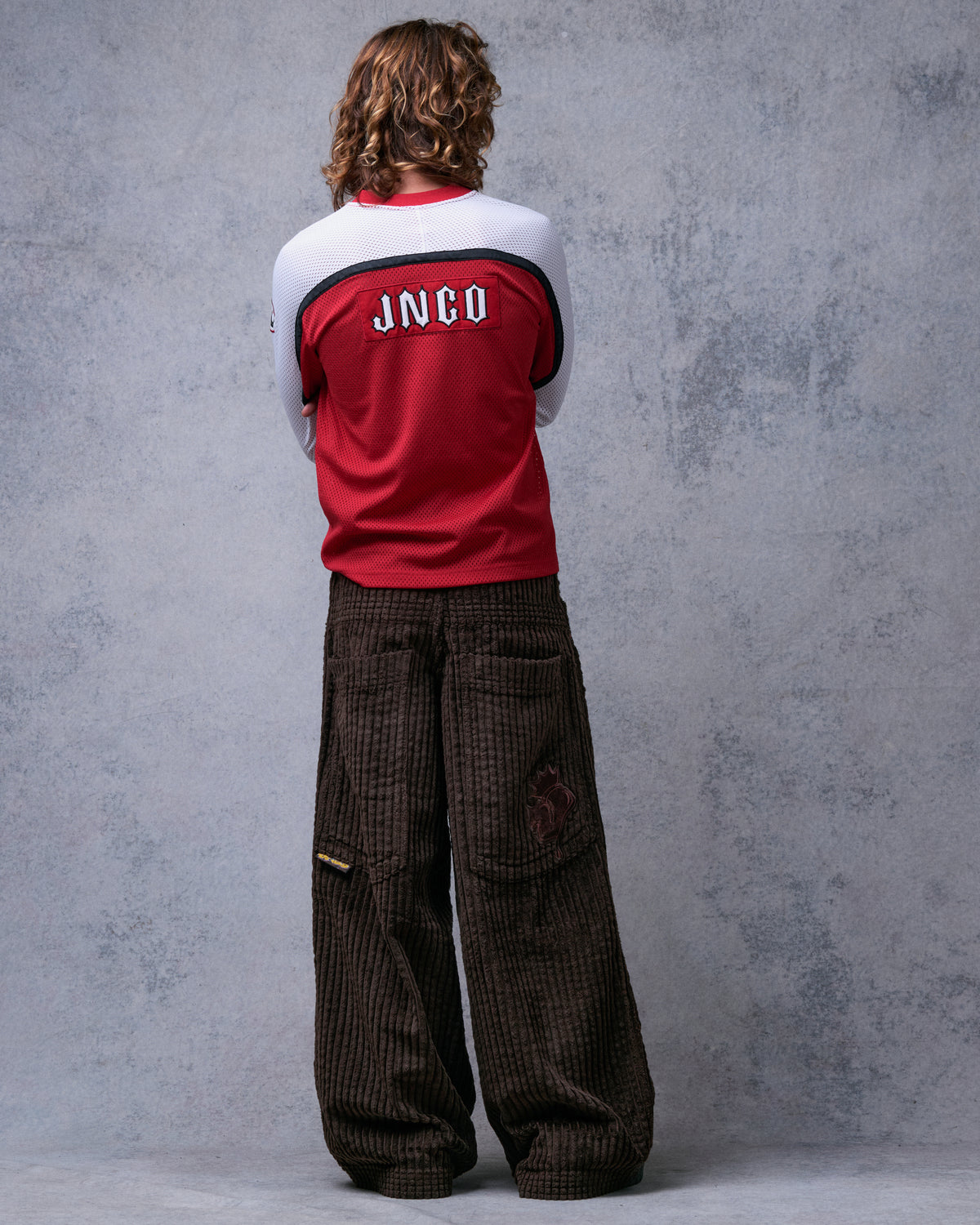 Model wearing brown wide-leg corduroy pants, straight back view with two back pockets and side tab