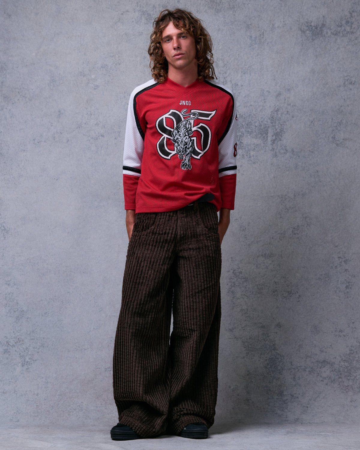 Model wearing brown wide-leg corduroy pants with a red jersey, full-length front view
