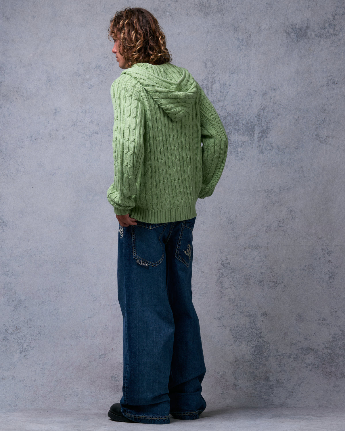Model wearing dark stone wash wide-leg jeans, back three-quarter view showing tribal-embroidered back pockets