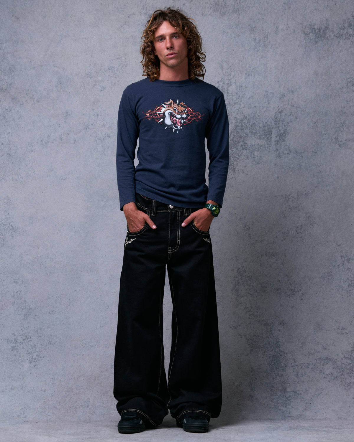 Model wearing black wide-leg jeans with cream contrast stitching, hands in front pockets, full front view