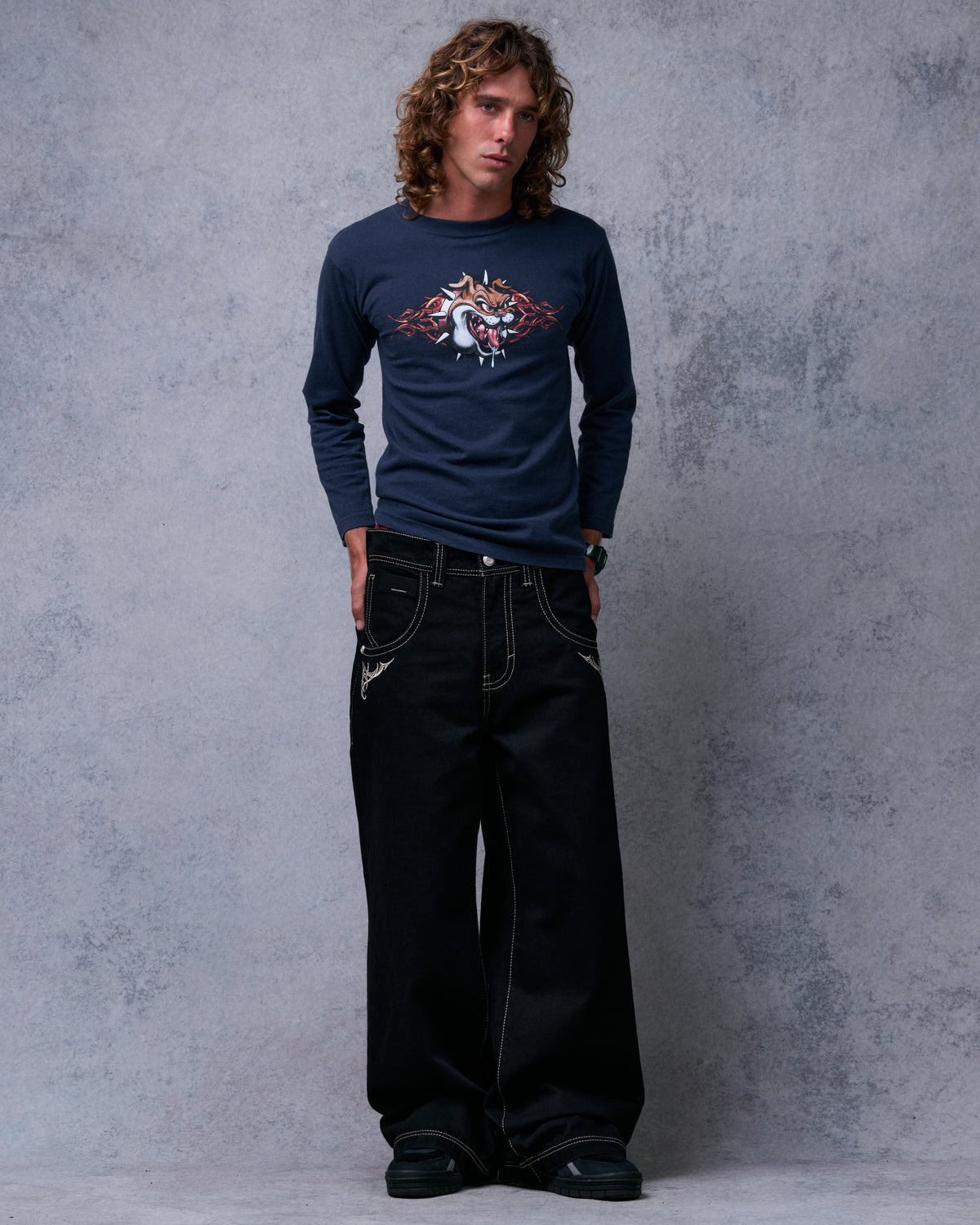 Model wearing black wide-leg jeans, front view, legs apart showing the wide hems over sneakers