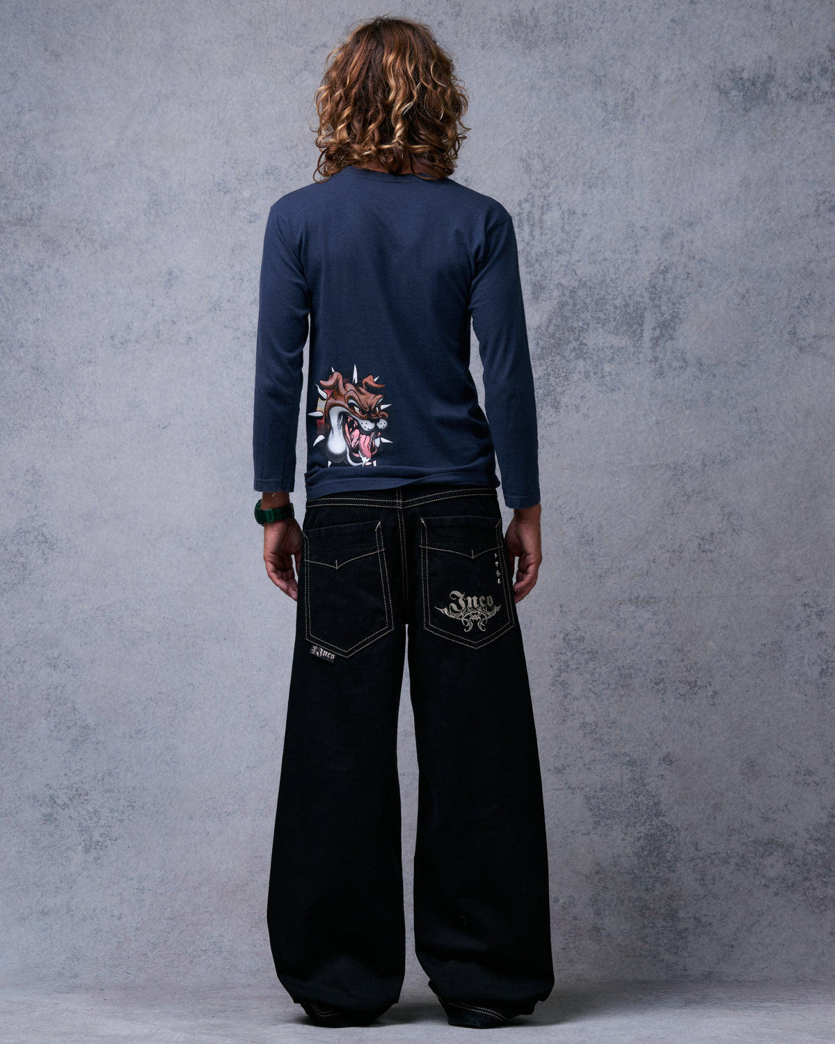 Model wearing black wide-leg jeans, back view, showing tribal Jnco embroidery on the back pocket