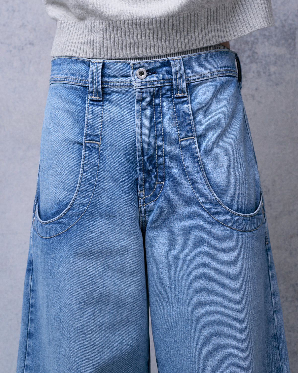 Close-up of the front of the light stone wash jeans showing the button fly, belt loops and curved front pockets