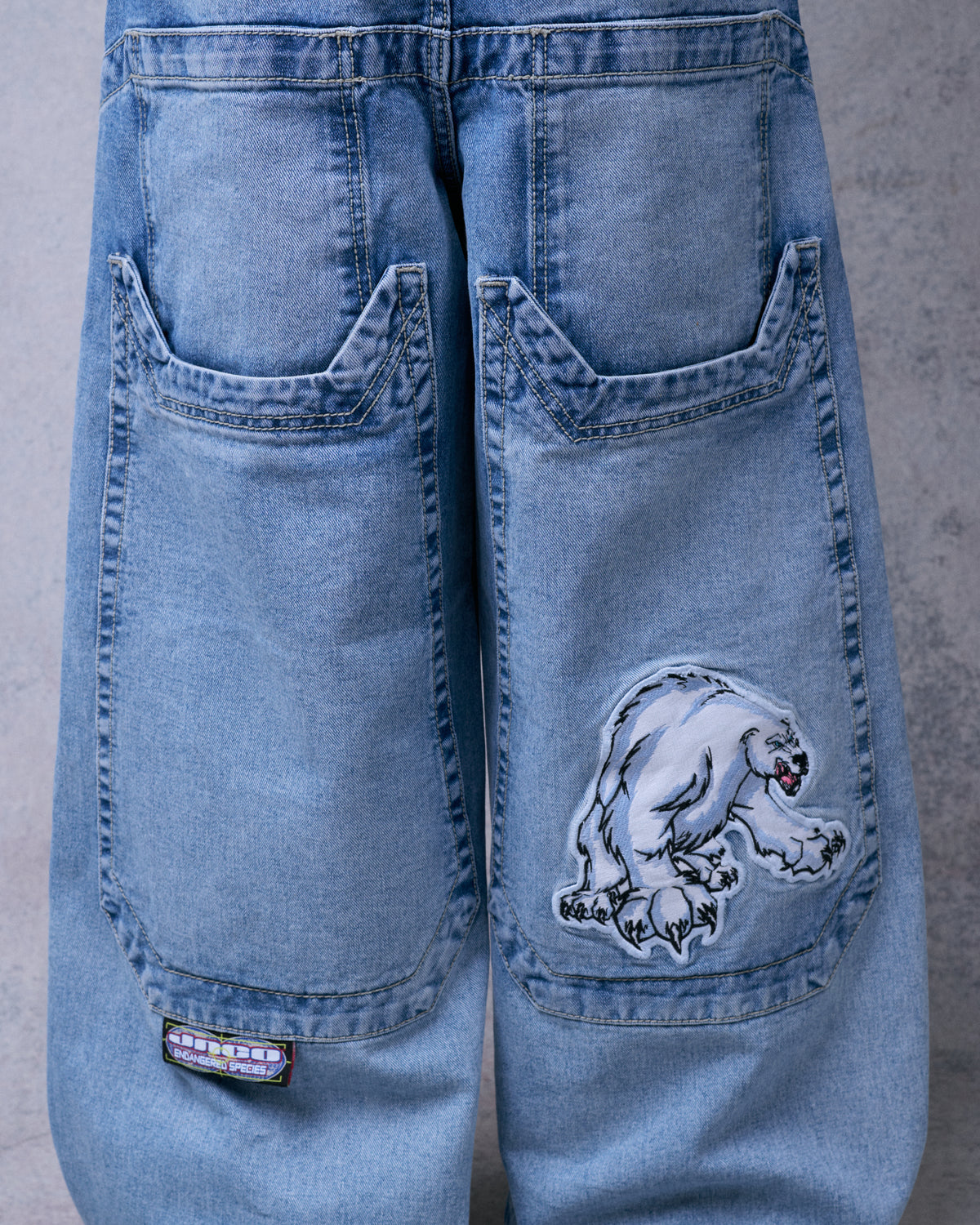 Back of the jeans showing oversized lower pockets, a polar bear patch on the right pocket and a woven label tab