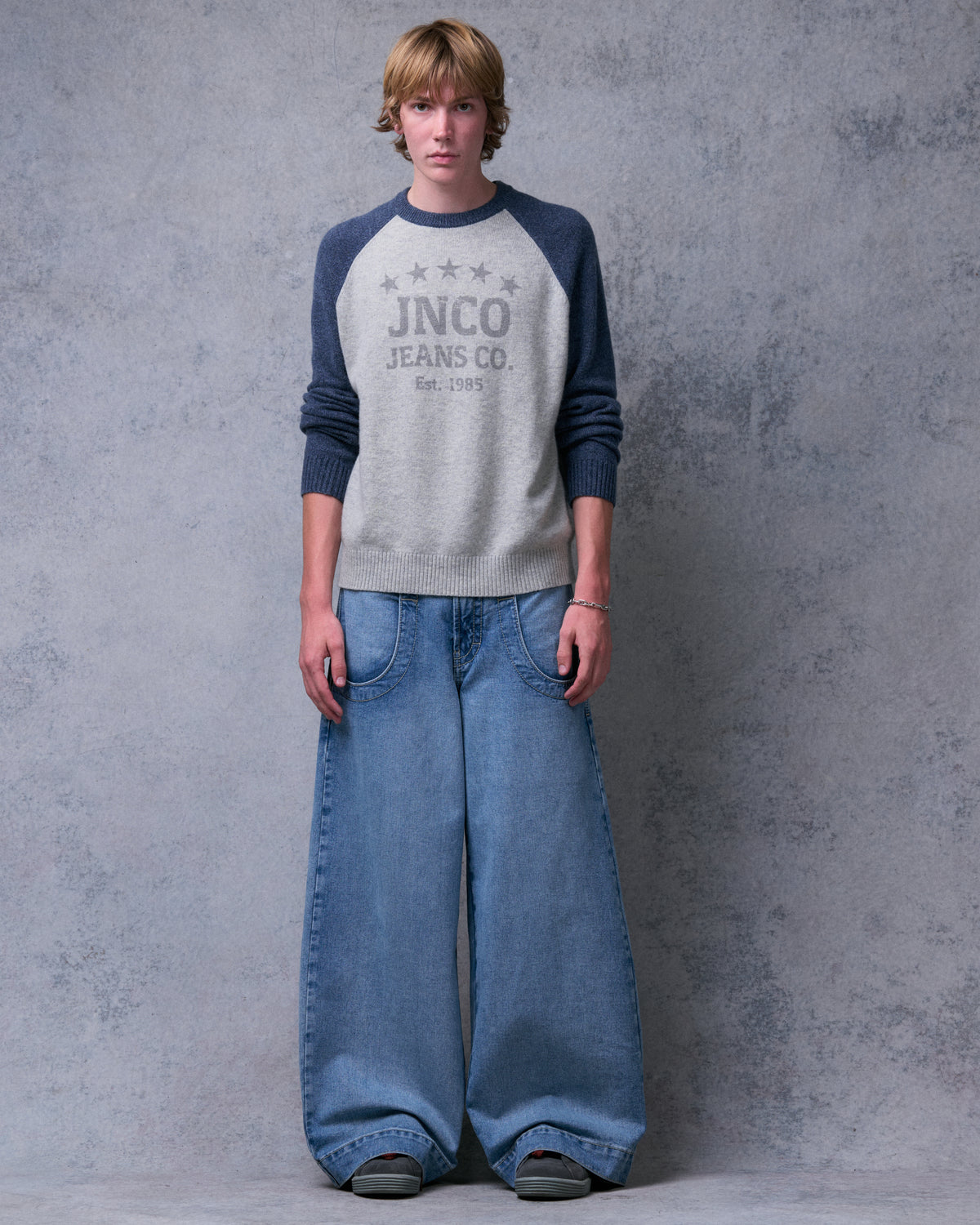 Model wearing light stone wash wide-leg jeans with a gray raglan sweater, front view