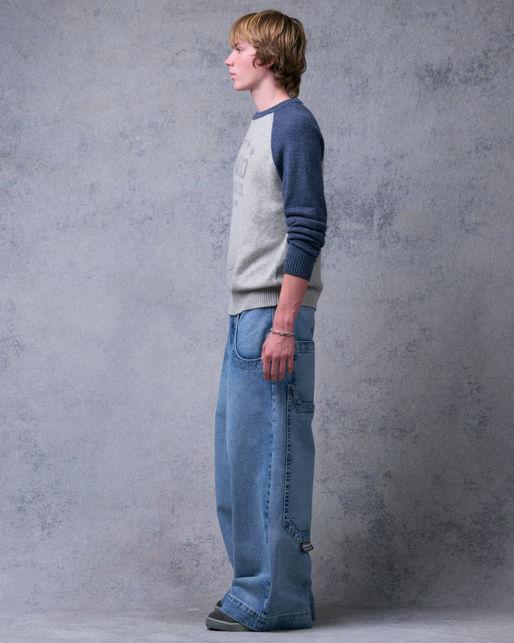 Model wearing the wide-leg jeans in side profile, showing the long side pocket and a small leg label