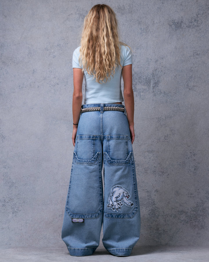 Model wearing light stone wash wide-leg jeans, back view showing four back pockets and polar bear patch