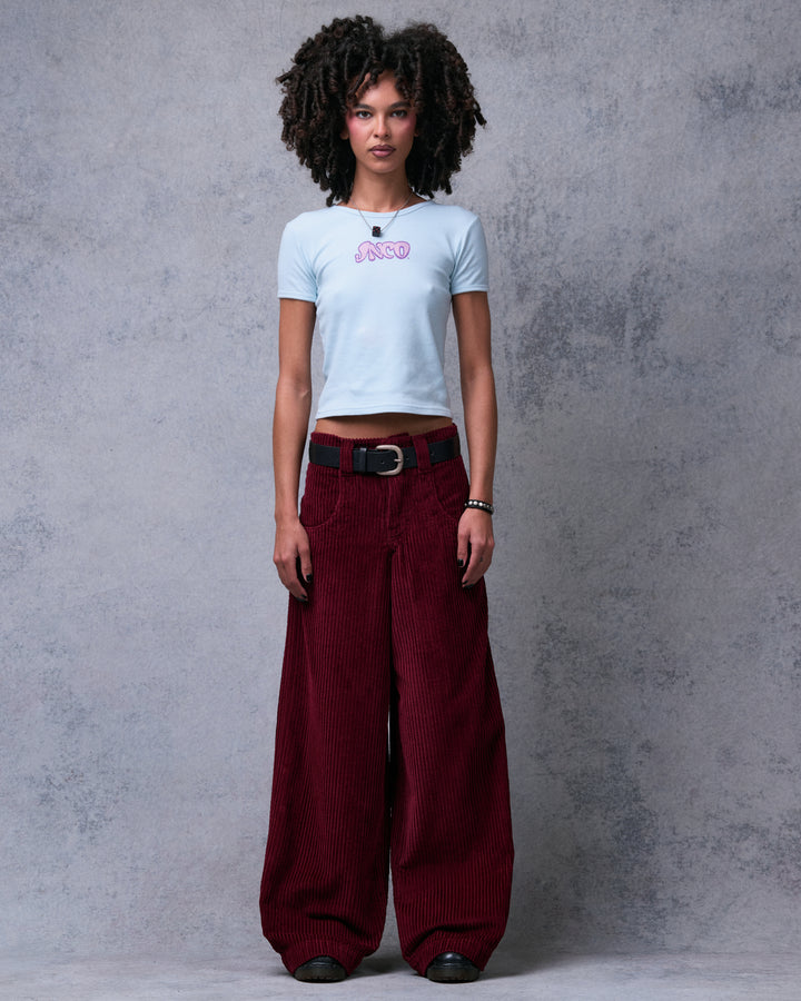 Model standing straight in burgundy wide-leg corduroy pants with a black belt, full front view